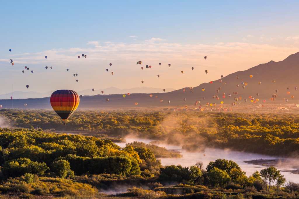 Hot air balloons flying over the Rio Grande River at sunrise