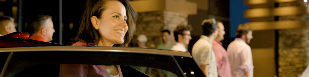 Woman exiting a black vehicle with a smile